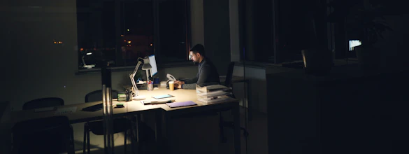Salarié qui travaille tard le soir dans un bureau peu éclairé, signe de stress au travail