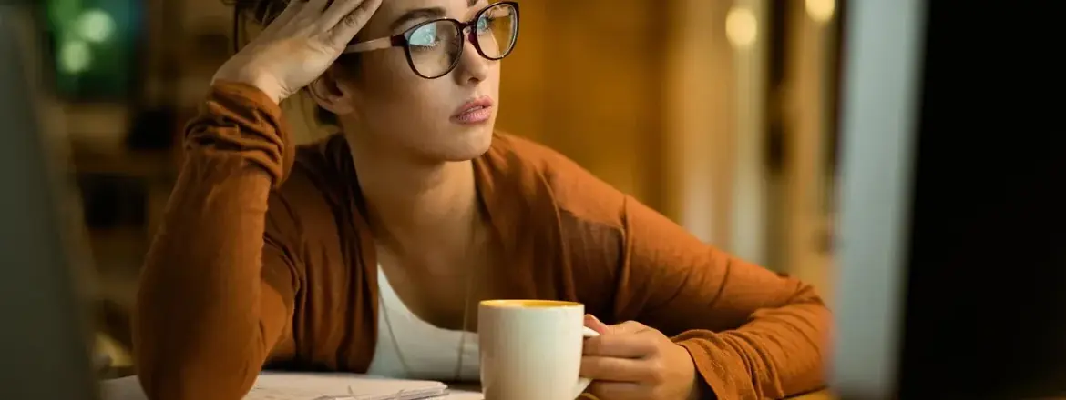 Jeune femme assise à son bureau, la main posée sur la poitrine, qui respire lentement pour se calmer